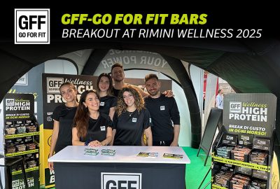 GFF team at Rimini Wellness 2025 booth with GO FOR FIT protein bars and branded promotional materials on display.
