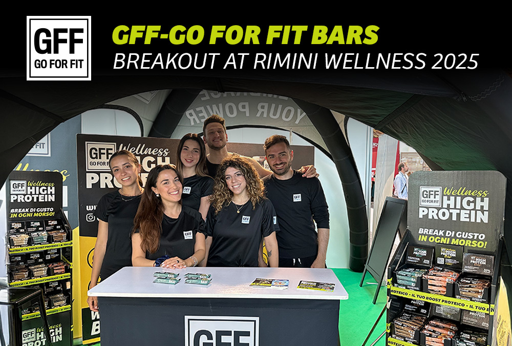 GFF team at Rimini Wellness 2025 booth with GO FOR FIT protein bars and branded promotional materials on display.